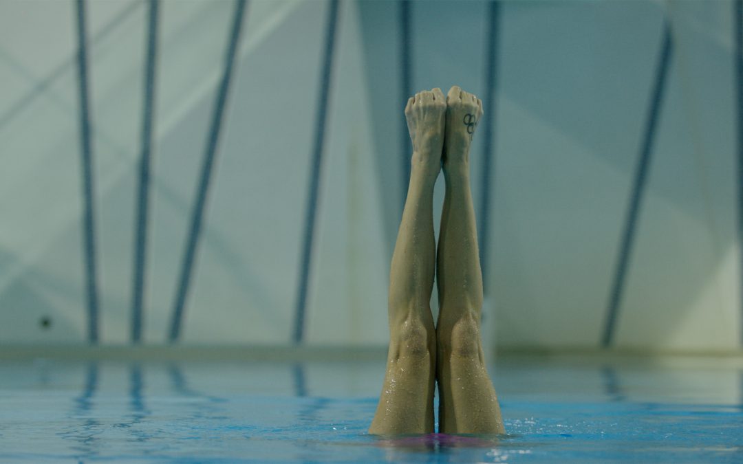 Swimmer head down in a pool with only legs above water