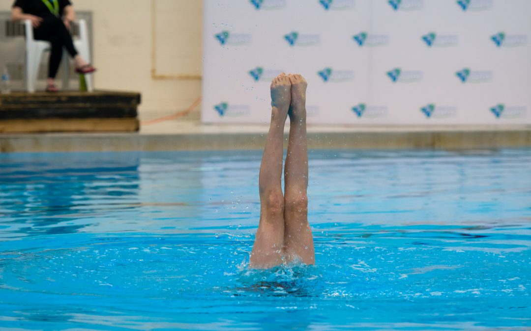 an artistic swimmer holding a position feet first
